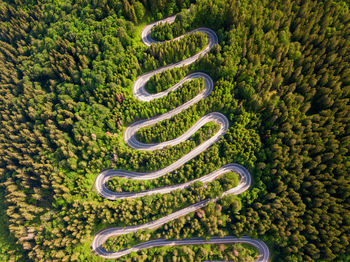 Winding road through the forest, from high mountain pass, in summer time. aerial view by drone