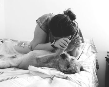 Woman playing with dog on bed at home