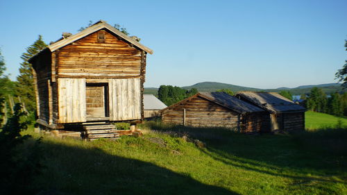 Wooden house on field against clear sky