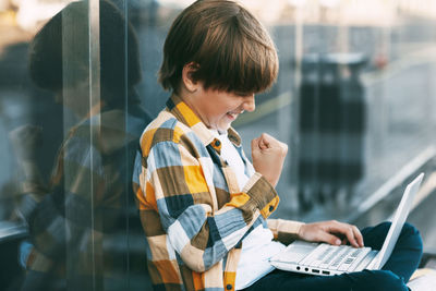 Rear view of boy looking through mobile phone