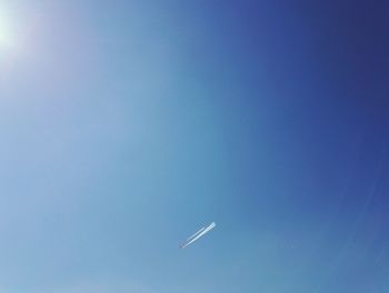Low angle view of airplane flying against clear blue sky