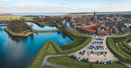 High angle view of city by river against sky