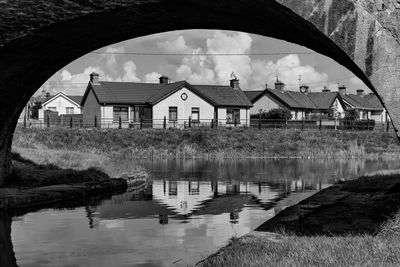 Houses by lake against sky seen through house