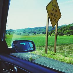 Close-up of road sign on field against sky