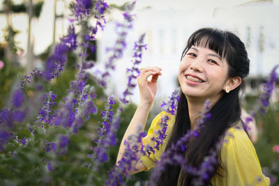 Portrait of smiling young woman blowing flowers