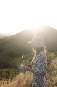 Side view of woman standing on field against clear sky