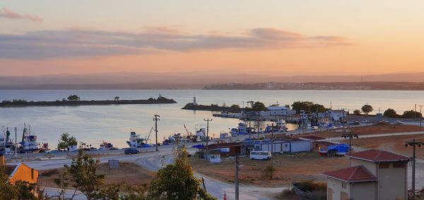 High angle view of sea and buildings against sky at sunset