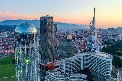 Modern buildings in city against sky during sunset