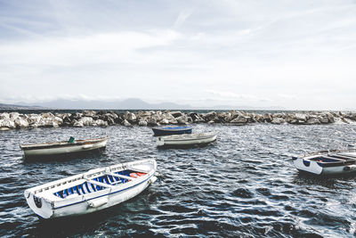 Boats moored at calm sea against the sky