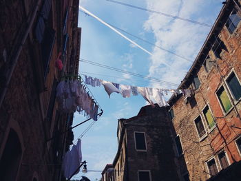 Clothes hanging on cable amidst buildings against sky