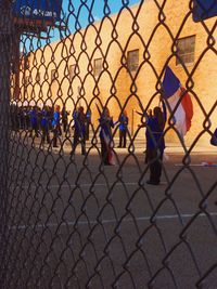 People standing by chainlink fence