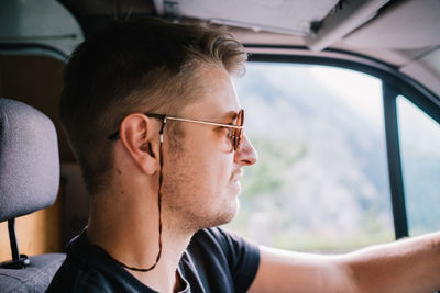 Profile view of young man wearing sunglasses while driving car