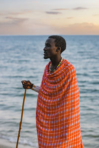 Man looking away while standing in sea against sky