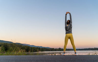 Full length of woman doing yoga against sky during sunset
