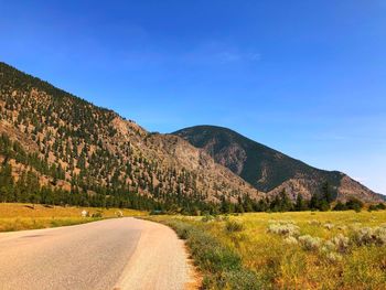 Road by mountain against clear blue sky