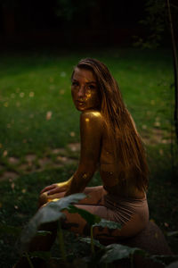 Young woman with golden skin sitting in the garden