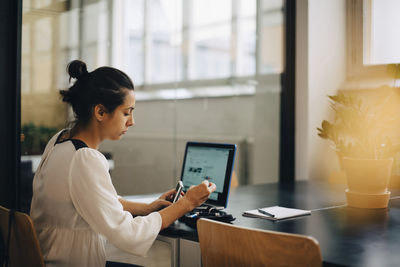 Businesswoman checking blood sugar level while using laptop at desk