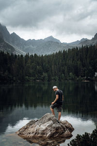 Rear view of man standing by lake