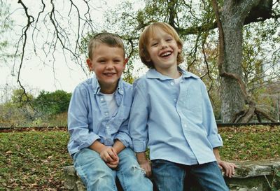 Portrait of happy boy on grass against trees