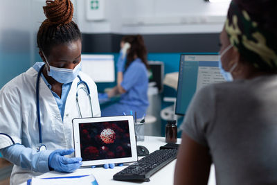 Doctor showing digital tablet to patient at clinic