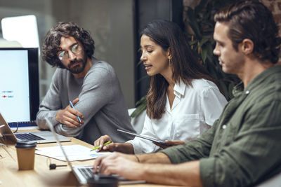 Businesswoman explaining business strategy to colleagues on document in meeting at office