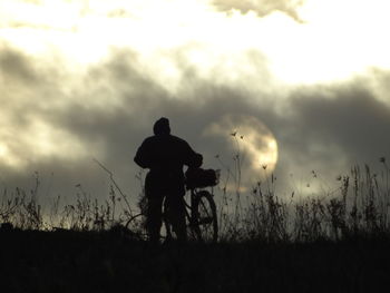 Rear view of silhouette man standing on field against sky