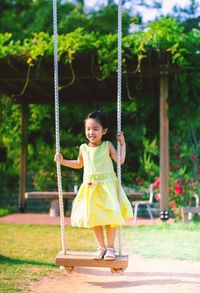 Portrait of happy girl standing on grass against trees