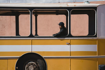 Man looking away while sitting in bus seen through window