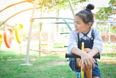 Thoughtful girl sitting on spring ride at park