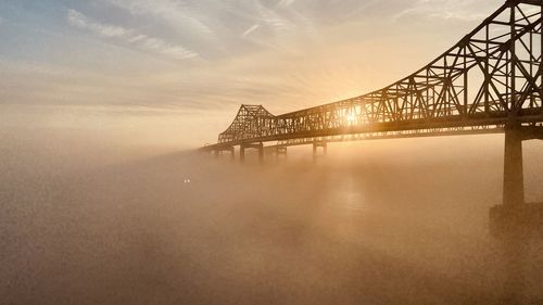 Bridge over river against sky during sunset