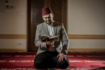 Full length of young man sitting on book