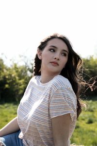 Portrait of beautiful young woman standing against sky