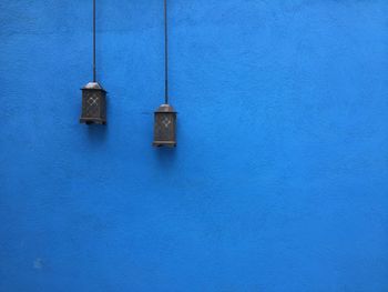 Lanterns hanging by blue wall