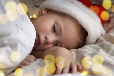 Cute sleeping young boy in santa claus hat. christmas light. winter holiday. toddler baby christmas.