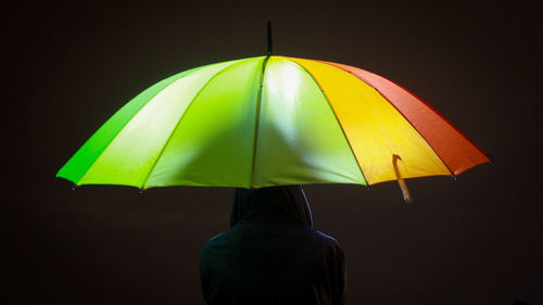 Rear view of person holding multi colored umbrella