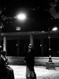 Rear view of man and woman standing on street at night