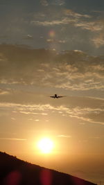 Silhouette airplane flying against sky during sunset