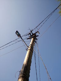 Low angle view of electricity pylon against clear blue sky