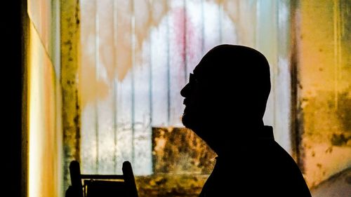 Close-up portrait of silhouette person standing against window