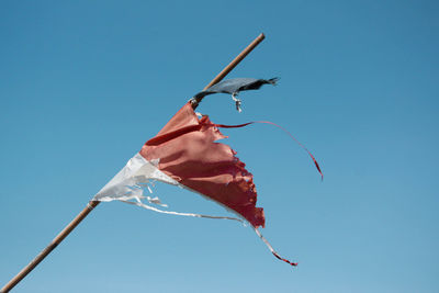 Low angle view of red flags against clear blue sky