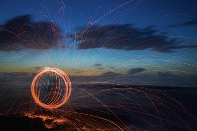 Light trails on field against sky at night