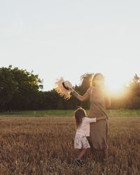 Full length of woman with arms raised on field against sky