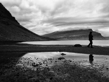 Man walking on lake against sky