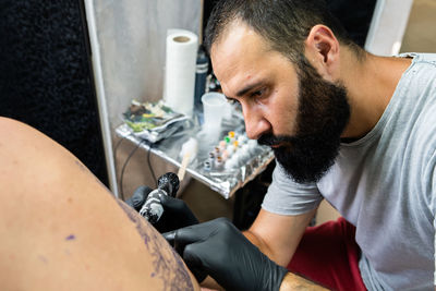 Close-up of artist tattooing customer in studio