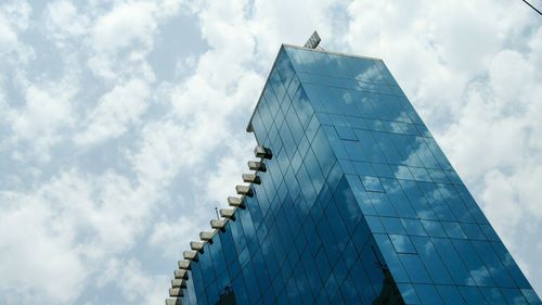 Low angle view of office building against cloudy sky