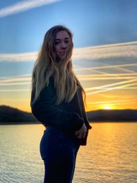 Portrait of woman standing against sea during sunset