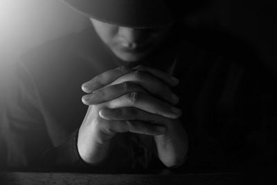 Close-up of young woman praying while sitting in darkroom