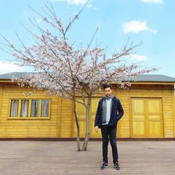 Portrait of man standing against wooden cottage