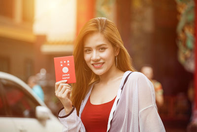Portrait of smiling beautiful woman with japanese passport in city 