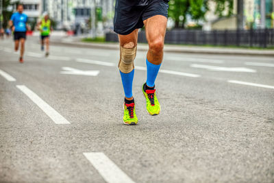 Legs runner man in compression socks and knee pads run race down street